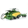 Front angled view of baler model with BaleCollect trailer in background showing detailed pickup assembly, PTO shaft, and open top panel